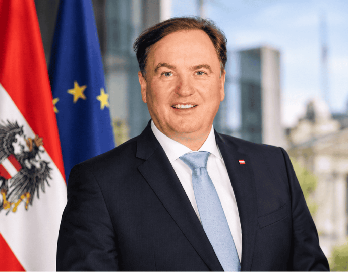 Portrait von Bernd Hinteregger vor den Flaggen &Ouml;sterreichs und der EU